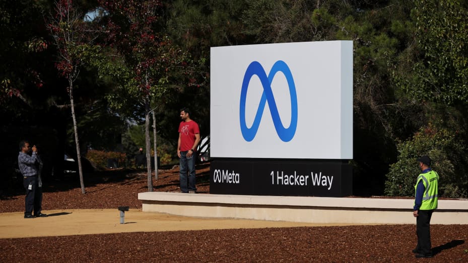 A man poses in front of a sign of Meta, the new name for the company formerly known as Facebook, at its headquarters in Menlo Park, California, October 28, 2021.